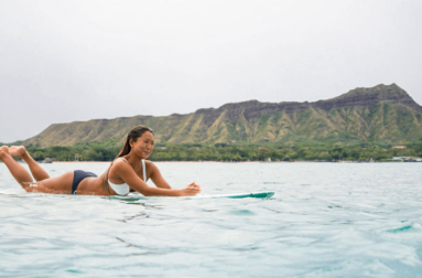 Surfer girl on a board in front of Diamondhead